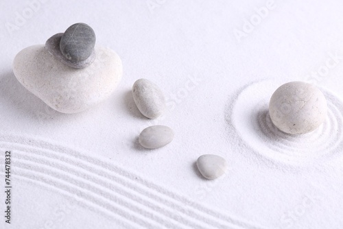 Photography Zen garden stones on white sand with pattern, flat lay