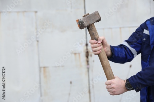 Man with sledgehammer outdoors, closeup. Space for text photo