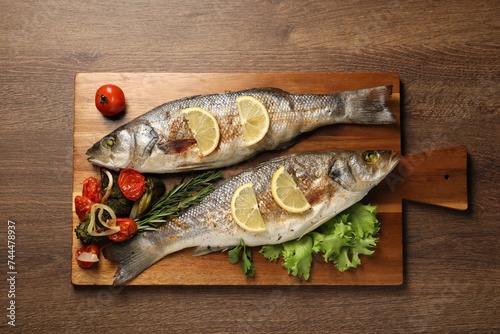 Delicious baked fish and vegetables on wooden table, top view
