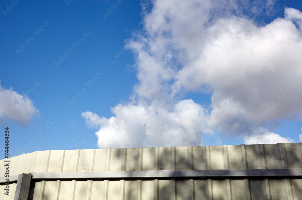 Corrugated steel fence against blue sky. Corrugated metal texture surface or galvanize steel Corrugated steel fence against blue sky. Corrugated metal texture surface or galvanize steel