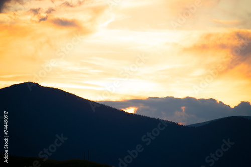 Sunset in the mountains. Silhouettes of fir trees on a mountainside in the sunset light. dark evening photo