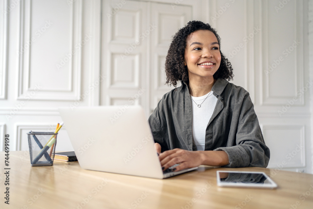 Joyful woman engaged in work on her laptop in a chic, bright room. Joyful woman engaged in work on her laptop in a chic, bright room.