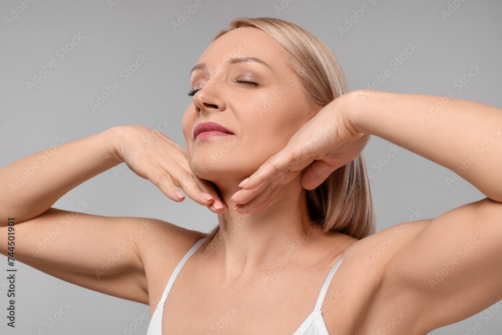 Beautiful woman touching her neck on grey background Beautiful woman touching her neck on grey background