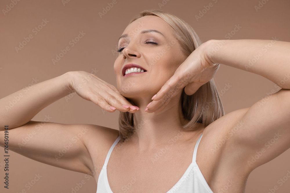 Beautiful woman touching her neck on beige background Beautiful woman touching her neck on beige background