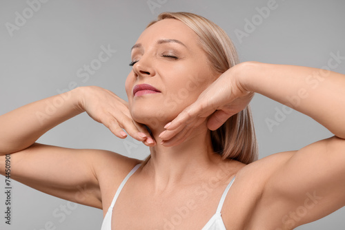 Beautiful woman touching her neck on grey background