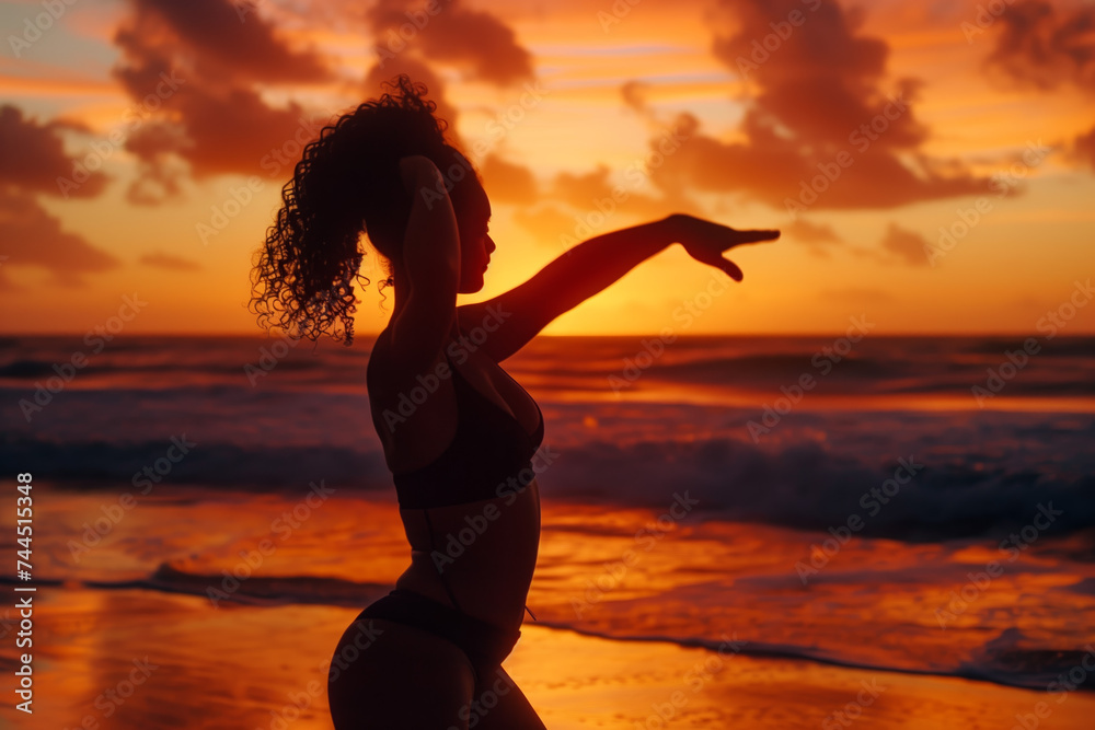 Beach Sunset Dance Silhouette. Woman in silhouette performing a dance pose on the beach at sunset.