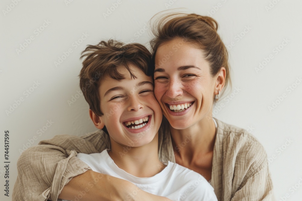 A woman and a boy smile and hug, sharing a happy gesture for the camera A woman and a boy smile and hug, sharing a happy gesture for the camera