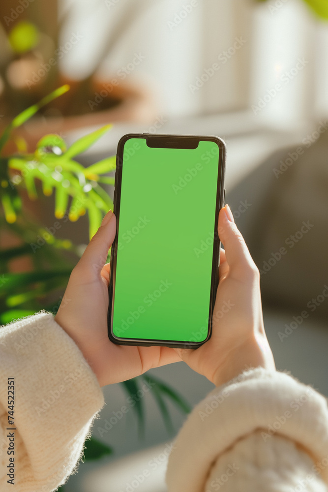 Close-up of female hands holding smartphone with green screen, ideal for design mockups.