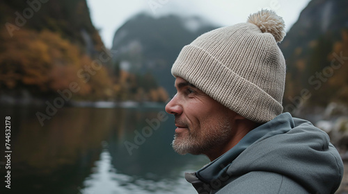 portrait of a man wearing a cream knitted beanie hat outdoors by the lake