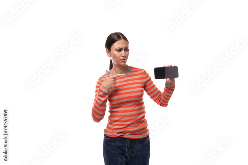 30 year old pretty woman dressed in a casual orange sweater shows the screen of a smartphone with a mockup