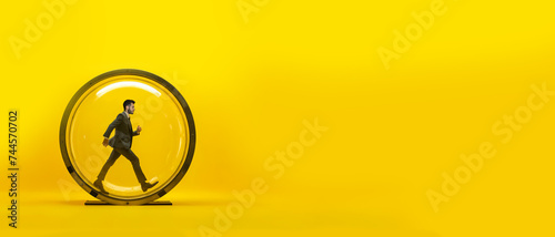 un homme en costume en train de courir dans une roue pour hamster géante - fond jaune photo