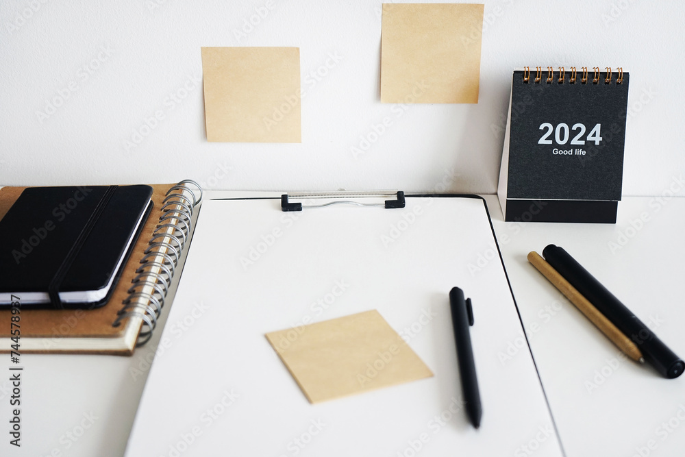 Clip folder with paper next to notepads, calendar, stickers and pens on white background Clip folder with paper next to notepads, calendar, stickers and pens on white background