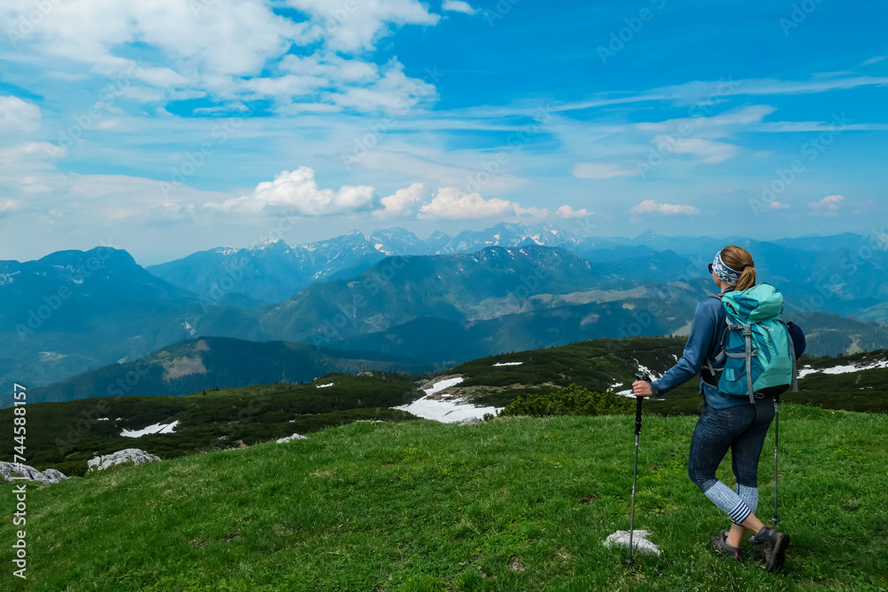 Hiker woman on top of mount Kriznik, Carinthia, border Austria Slovenia. Alpine meadow with scenic view of mountain range Karawanks, Slovenian Austrian Alps. Hiking trail Petzen, Bleiburg, Völkermarkt