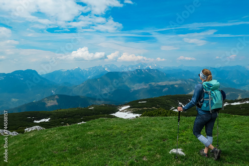 Hiker woman on top of mount Kriznik, Carinthia, border Austria Slovenia. Alpine meadow with scenic view of mountain range Karawanks, Slovenian Austrian Alps. Hiking trail Petzen, Bleiburg, Völkermarkt