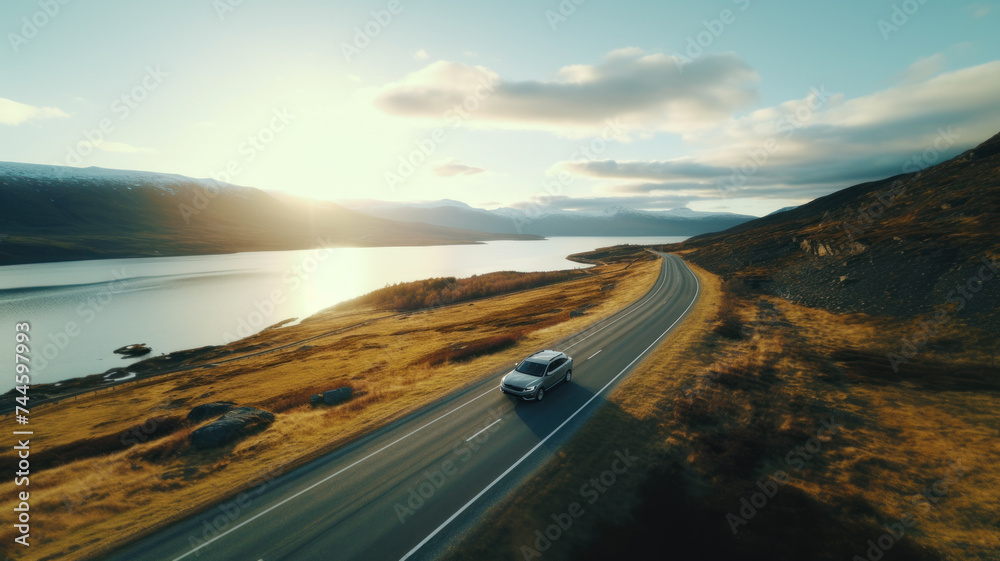 A car drives along an empty road over the sea at sunset.	