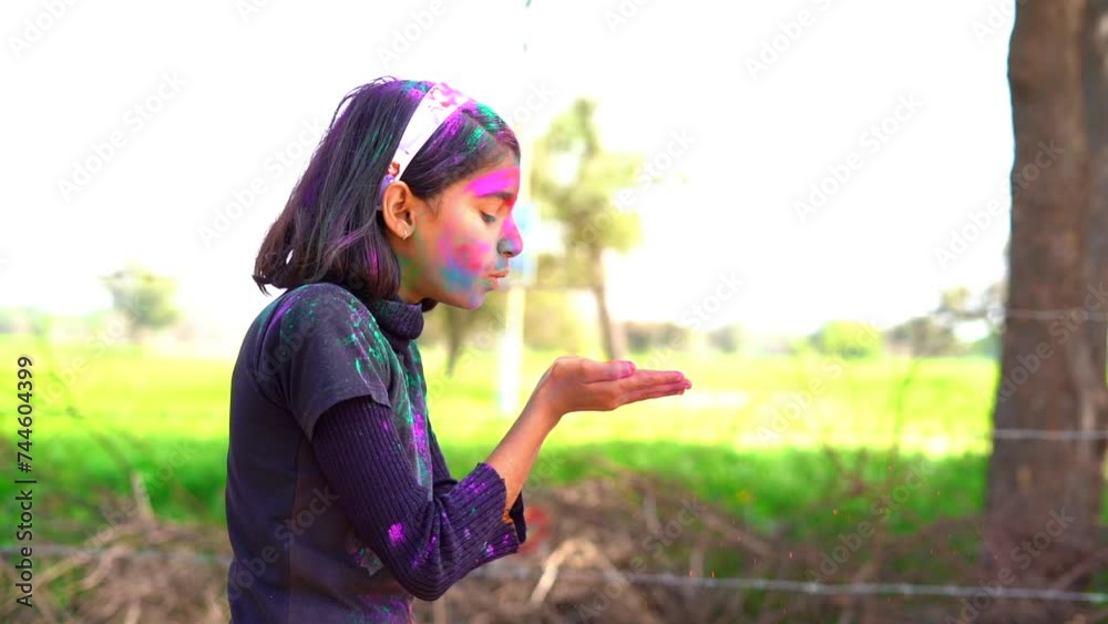 Indian Little girl showing colourful palm and celebrating holi with colour splash