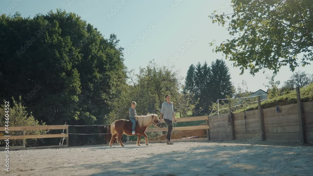 Young boy riding small brown pony on a small local farm in the countryside. Enoying pony riding on a sunny day. Young boy riding small brown pony on a small local farm in the countryside. Enoying pony riding on a sunny day.