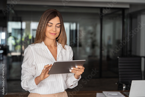 Latin Hispanic mature adult professional business woman looking at online trade app. European businesswoman CEO holding digital tablet using fintech tab application standing at workplace in office. Free Download Latin Hispanic mature adult professional business woman looking at online trade app. European businesswoman CEO holding digital tablet using fintech tab application standing at workplace in office. - GFXLoad