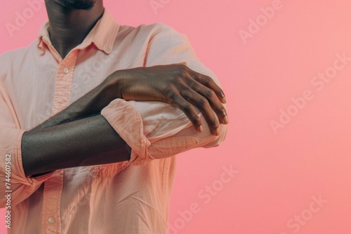 Black man touching his forearm with hand on pink background