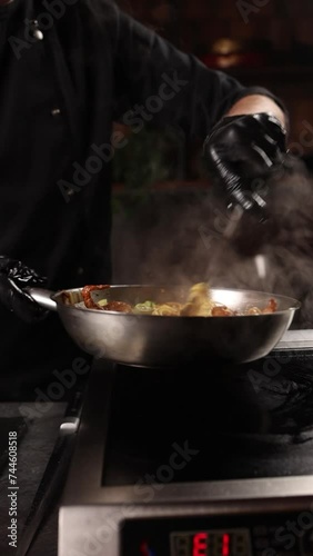 Chef prepares noodles with meat and vegetables