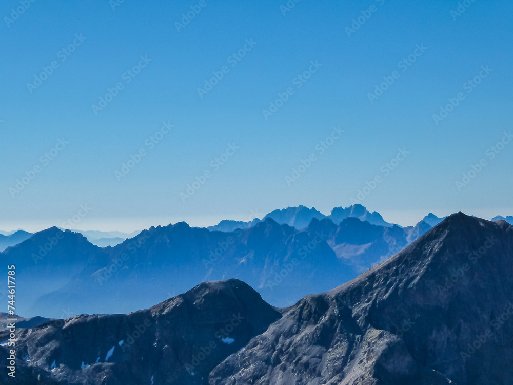 Panoramic view from majestic mountain peak of Hochschober, Schober Group, High Tauern National Park, East Tyrol, Austria. Wanderlust Austrian Alps in summer. Misty rugged ridges against clear blue sky Panoramic view from majestic mountain peak of Hochschober, Schober Group, High Tauern National Park, East Tyrol, Austria. Wanderlust Austrian Alps in summer. Misty rugged ridges against clear blue sky