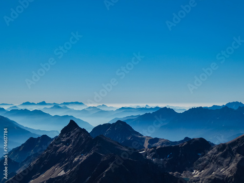 Panoramic view from majestic mountain peak of Hochschober, Schober Group, High Tauern National Park, East Tyrol, Austria. Wanderlust Austrian Alps in summer. Misty rugged ridges against clear blue sky © Chris