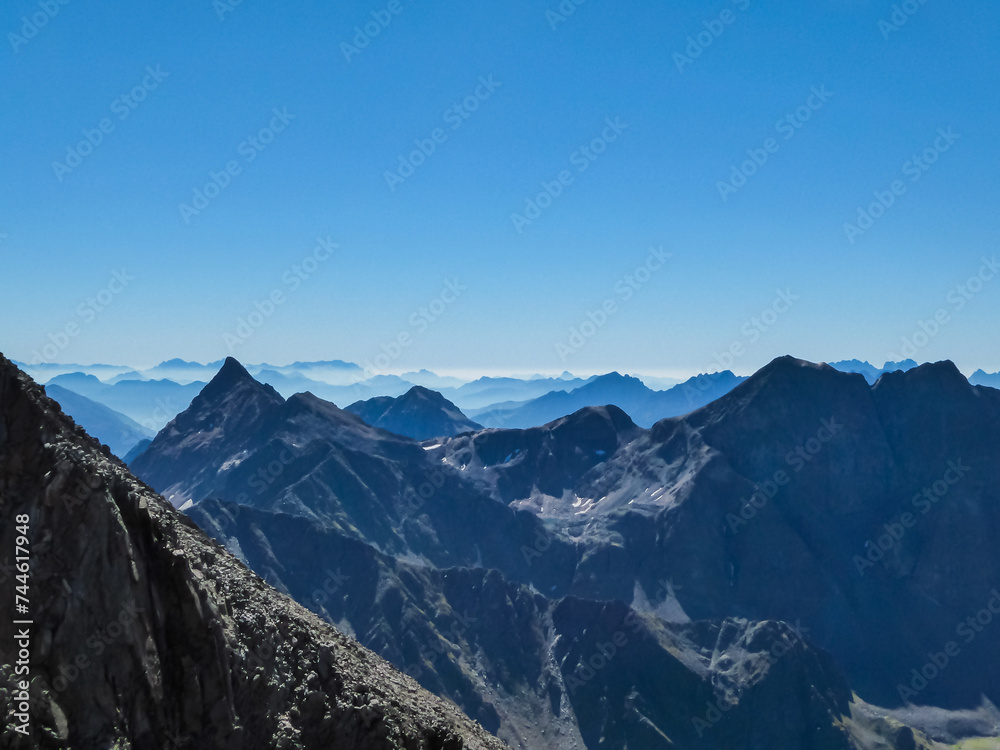 Panoramic view from majestic mountain peak of Hochschober, Schober Group, High Tauern National Park, East Tyrol, Austria. Wanderlust Austrian Alps in summer. Misty rugged ridges against clear blue sky Panoramic view from majestic mountain peak of Hochschober, Schober Group, High Tauern National Park, East Tyrol, Austria. Wanderlust Austrian Alps in summer. Misty rugged ridges against clear blue sky