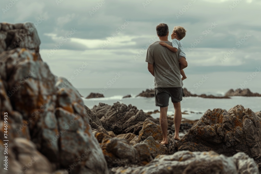 Walking on the rocks at the beach, dad and son hugging