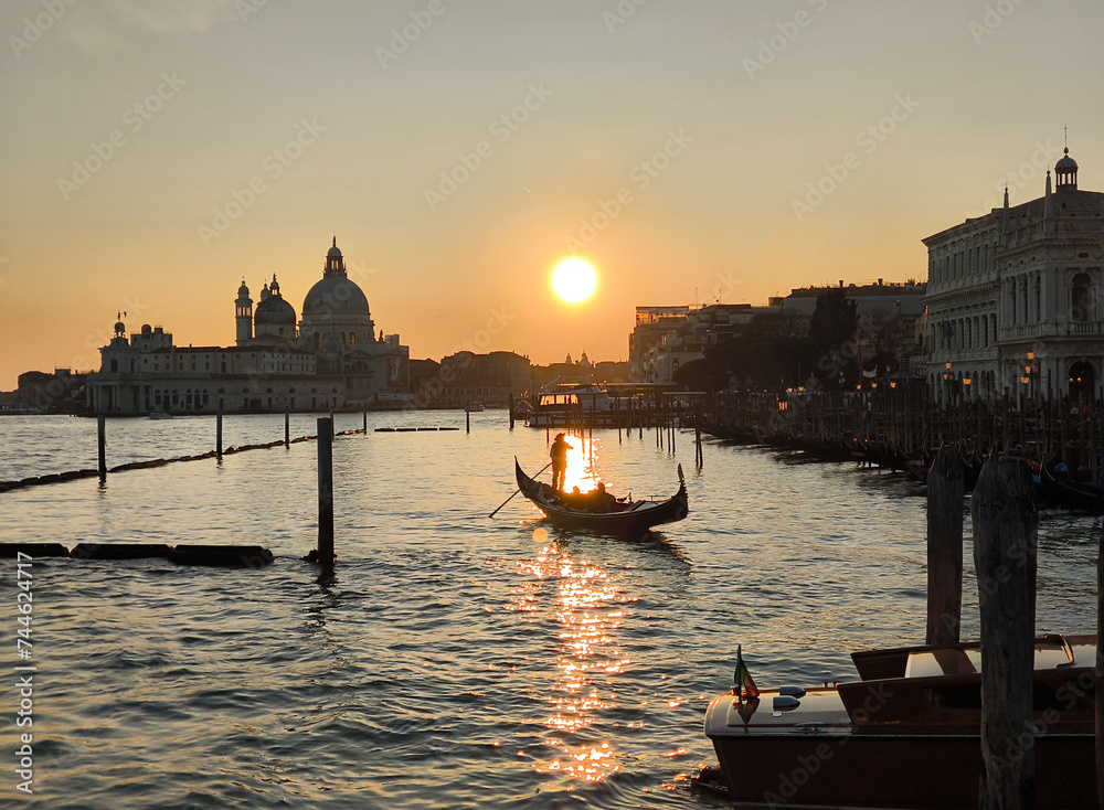 Venice, gondola at sunset in the lagoon with the Basilica Della Salute in the background, romantic image