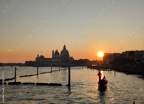 Venice, gondola at sunset in the lagoon with the Basilica Della Salute in the background, romantic image © Savinus