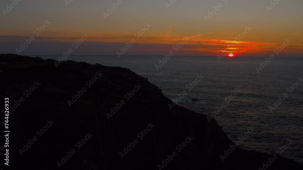 Camera flies over empty cliff at sunset dusk before night time. Vibrant red sun rays go through the atmospheric sky over the sea. Stunning natural beauty. Camera flies over empty cliff at sunset dusk before night time. Vibrant red sun rays go through the atmospheric sky over the sea. Stunning natural beauty.