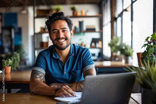 Smiling Hispanic entrepreneur with a tattoo, in a casual blue polo, at a workspace with a laptop, Generative AI