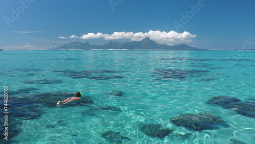 Woman snorkel crystal blue sea water. Person explore coral reef underwater wild life in sunny day. Outdoor lifestyle travel on summer holiday vacation. Tahiti exotic paradise island, French Polynesia