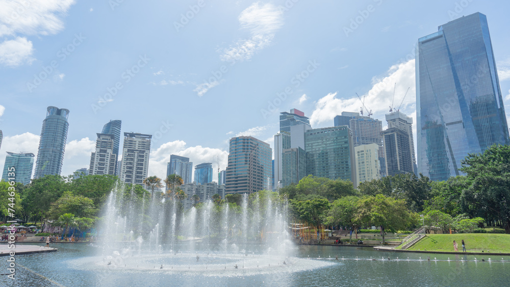 31 December 2023 in Malaysia A photo of a fountain dancing in a park. There is greenness among the trees amidst the large tall buildings in the heart of the city.