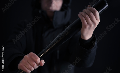 Male hooligan threatening in the dark with a baseball bat in his hands photo