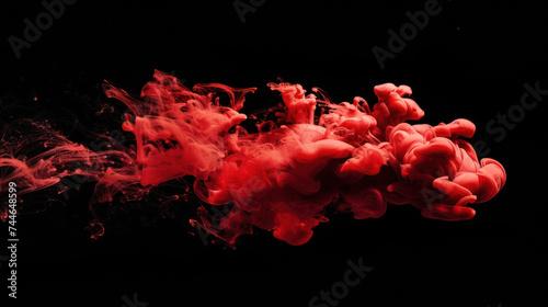 Red paint drop mixing in water towards to camera. Ink swirling underwater. Cloud of ink isolated on black background. Abstract smoke explosion effect with particles.