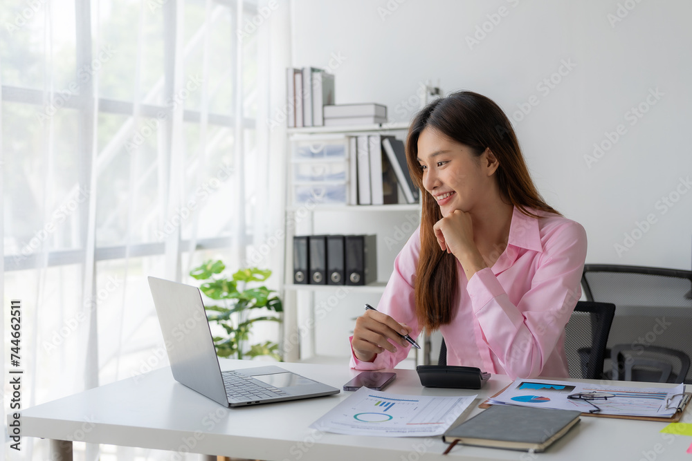 Annual summary report, laptop and paper placed at desk, Asian woman working online and planning financial data with laptop and succeeding with excited and happy face