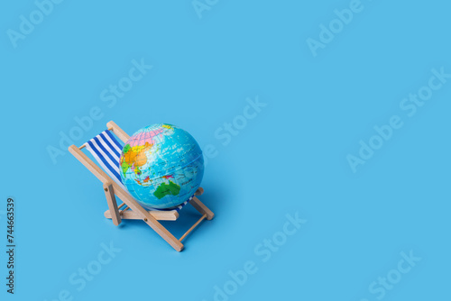 Beach lounger with globe, international holiday concepts, global relaxation, travel destinations, blue background