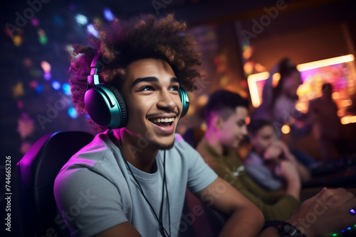 A young adolescent latin man is gaming on a computer with a headset on a computer while his friends are watching from behind gaming colorful computers fun