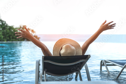 Holiday relaxation vacation of woman take it easy, happy life quality, resting on beach chair at swimming pool poolside beachfront resort hotel with summer sea sky ocean view background © Chinnapong