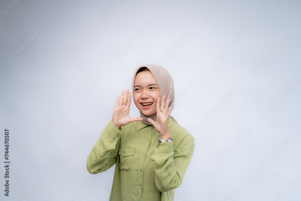 Announcement. Portrait Of Positive Happy Young asian woman wearing hijab using his hand near his mouth at Copy Space Advertising Your Text, Standing Isolated Over white Studio Background Announcement. Portrait Of Positive Happy Young asian woman wearing hijab using his hand near his mouth at Copy Space Advertising Your Text, Standing Isolated Over white Studio Background