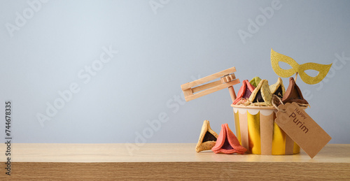Jewish holiday Purim concept with colorful hamantaschen cookies and carnival mask on wooden table over gray background photo