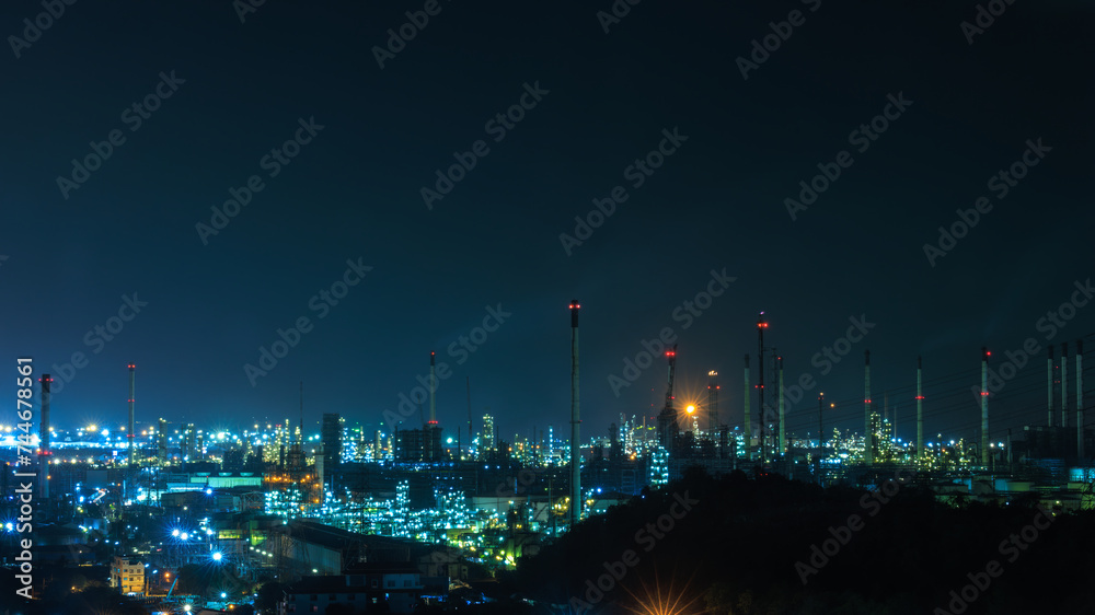 Fototapeta premium Panorama night cityscape and oil refinery, petroleum oil yard, tank storage field. Crude oil, natural gas. Nice lighting cover the city. Business and industrail, import and export, international 