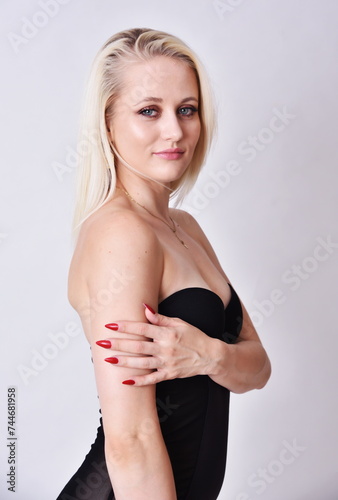 Blond caucasian woman, bright skin and blue eyes. Model in her 20's. Woman wearing tight, black dress.