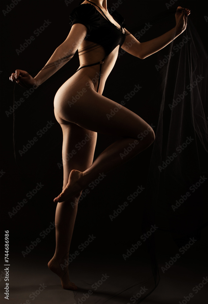 Beautiful girl body with black sexy underwear on a black background. A young sensual slender girl close up nudity. Beautiful girl body with black sexy underwear on a black background. A young sensual slender girl close up nudity.