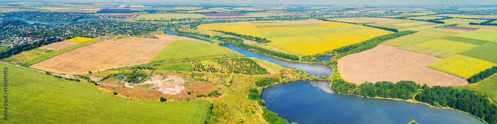 Sunny day in the countryside. Rural landscape in daylight. Aerial view of a meandering river and cultivated fields. Horizontal banner