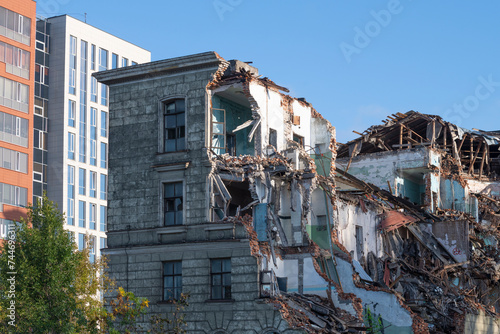 Old collapsed building against the background of new multi-storey buildings photo