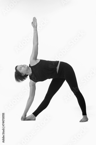 Triangle Pose Yoga (Utthita Trikonasana), Ashtanga yoga Side view of woman wearing sportswear doing Yoga exercise against white background. Black and white.