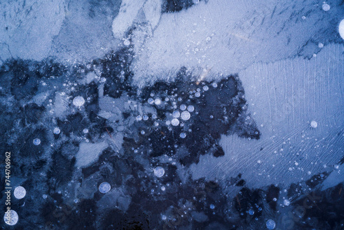Fototapeta Naklejka Na Ścianę i Meble -  Top view of air bubbles and formations formed on the surface of frozen water. Blue background.