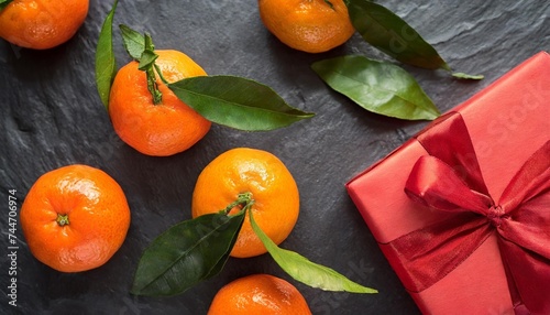 mandarines with leaves and red wrapping paper on a black stone background